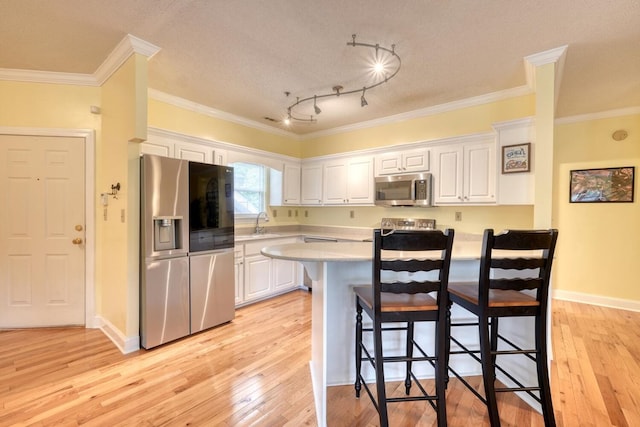 kitchen featuring light hardwood / wood-style flooring, stainless steel appliances, white cabinetry, and a textured ceiling