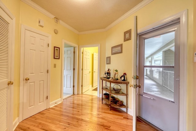 entryway with light hardwood / wood-style floors, a textured ceiling, and crown molding