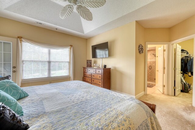 carpeted bedroom featuring ceiling fan, a textured ceiling, and a walk in closet