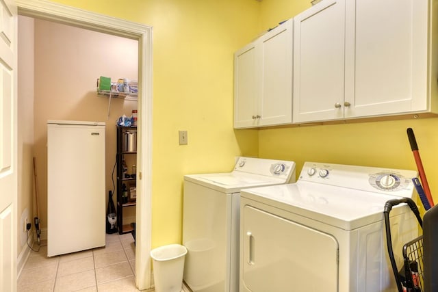 laundry room featuring light tile patterned flooring, washing machine and clothes dryer, and cabinets