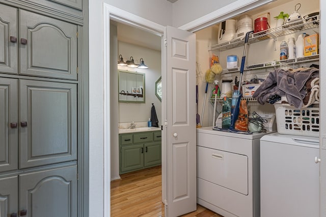 clothes washing area featuring a sink, light wood finished floors, laundry area, and washing machine and clothes dryer