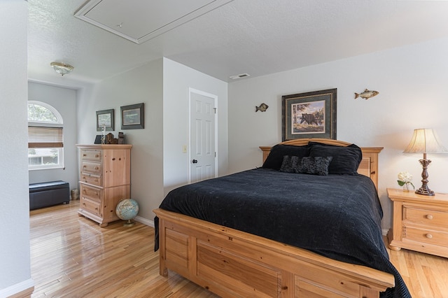 bedroom featuring visible vents, a textured ceiling, attic access, and light wood-type flooring