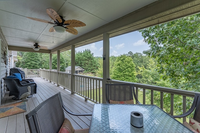 wooden deck with outdoor dining space and a ceiling fan