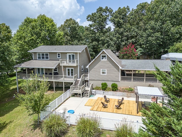 back of property featuring a wooden deck, a yard, a balcony, a fenced backyard, and a patio