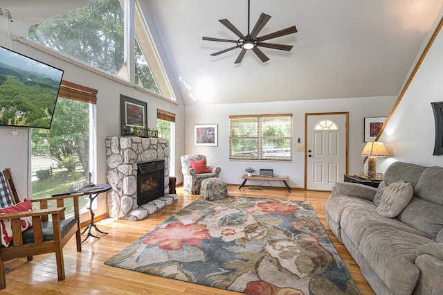 living area featuring wood finished floors, high vaulted ceiling, a fireplace, and ceiling fan