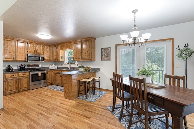 kitchen featuring a peninsula, dark countertops, brown cabinets, and stainless steel appliances