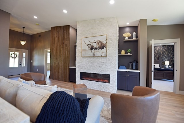 living area featuring light wood-style floors, a fireplace, recessed lighting, and built in features