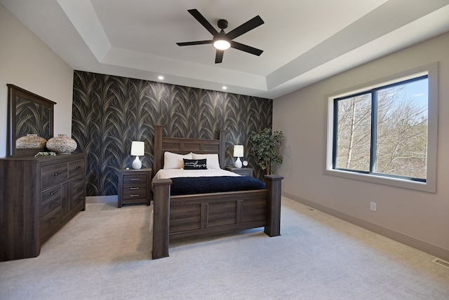 bedroom featuring an accent wall, a raised ceiling, baseboards, and wallpapered walls