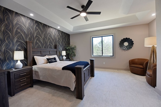 bedroom with wallpapered walls, baseboards, a raised ceiling, light colored carpet, and an accent wall