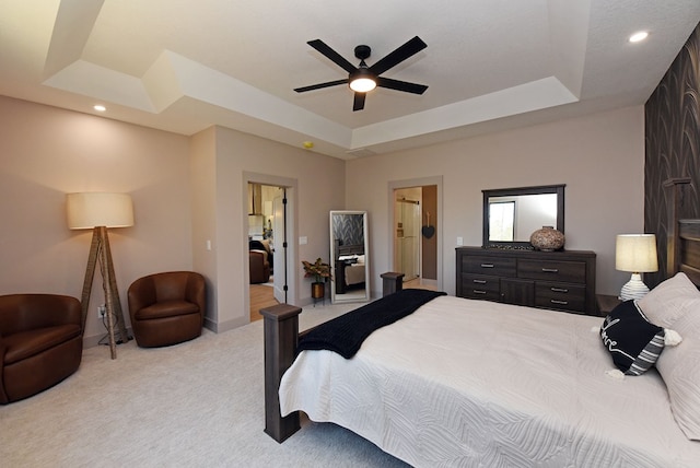 bedroom featuring light colored carpet, ceiling fan, ensuite bathroom, a tray ceiling, and recessed lighting