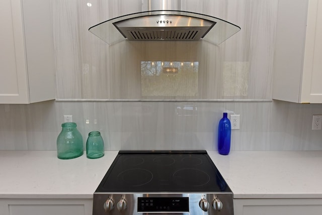 kitchen featuring white cabinets, stainless steel electric range oven, light stone countertops, range hood, and backsplash