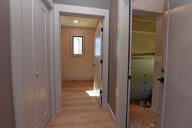 hall with light wood-style flooring and baseboards