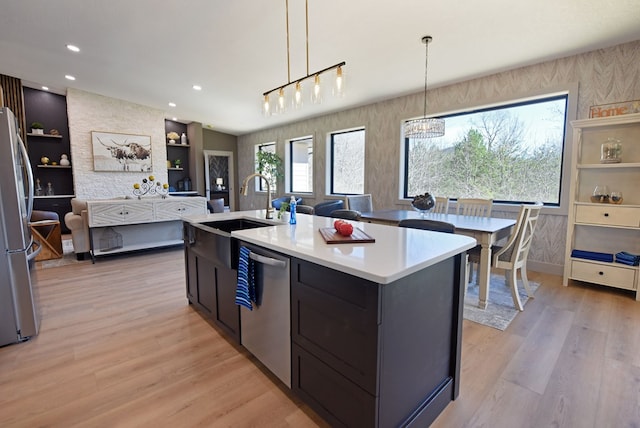 kitchen with light wood-style flooring, stainless steel appliances, a sink, and light countertops