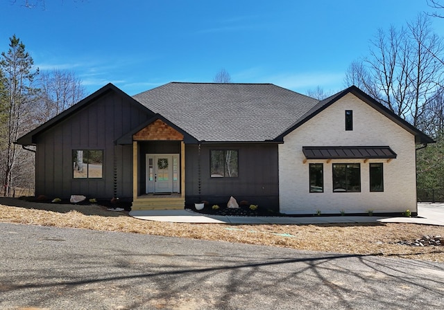 modern inspired farmhouse with a shingled roof and board and batten siding