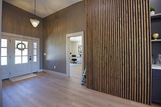 entrance foyer with a healthy amount of sunlight, light wood-style floors, baseboards, and high vaulted ceiling