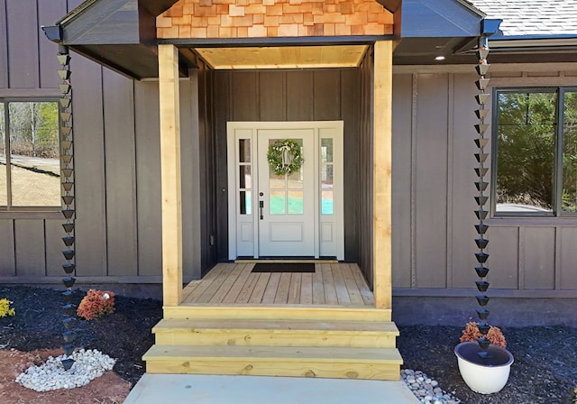 doorway to property featuring board and batten siding and roof with shingles