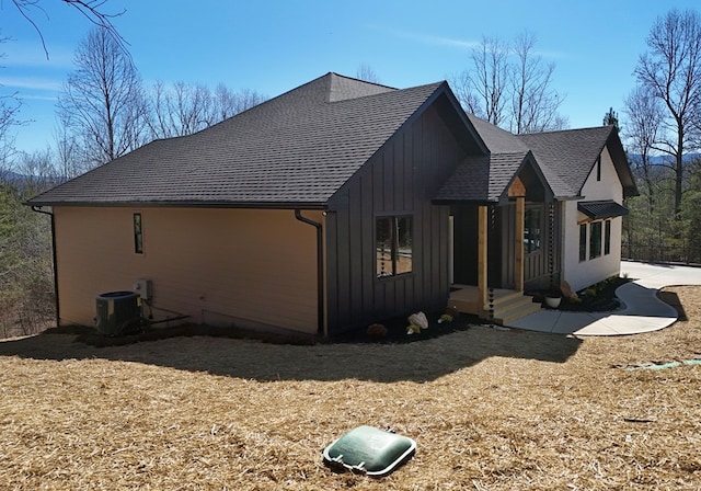 view of front of home with board and batten siding, roof with shingles, and central air condition unit