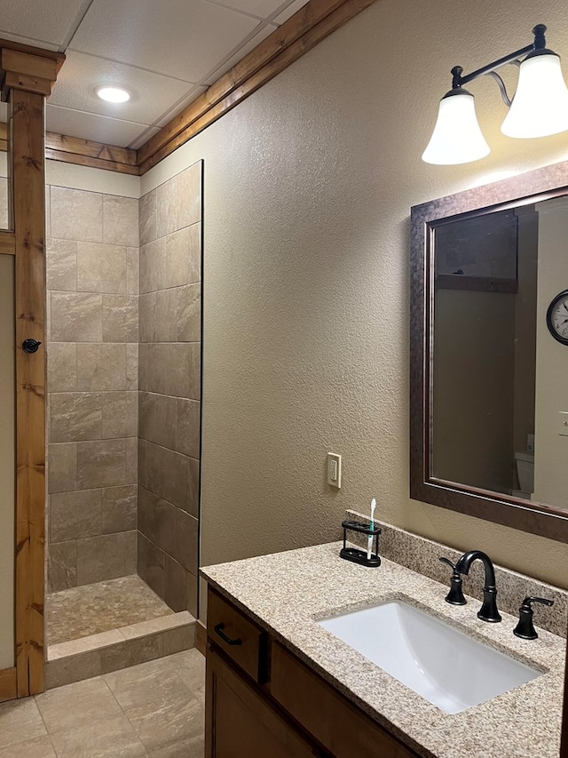 bathroom featuring vanity, a tile shower, toilet, and tile patterned floors