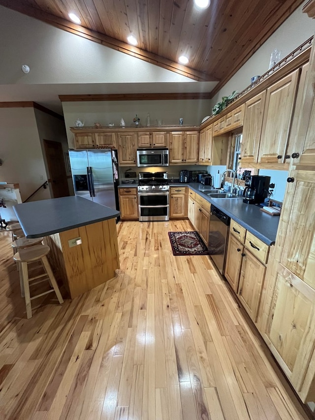 kitchen with lofted ceiling, light wood-type flooring, stainless steel appliances, sink, and a center island