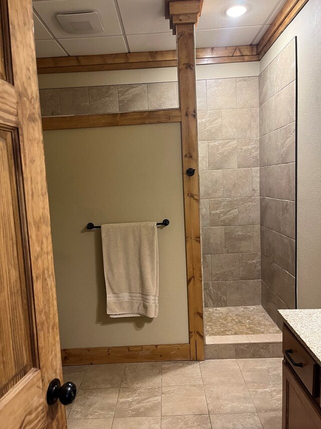 bathroom featuring vanity, tiled shower, and tile patterned flooring