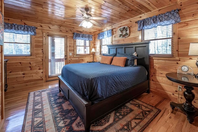 bedroom with access to exterior, wood finished floors, wood ceiling, and wooden walls