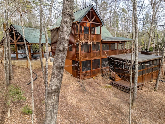 back of house featuring log veneer siding and a sunroom