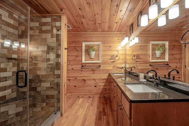 bathroom with double vanity, a stall shower, a sink, wood finished floors, and wooden ceiling