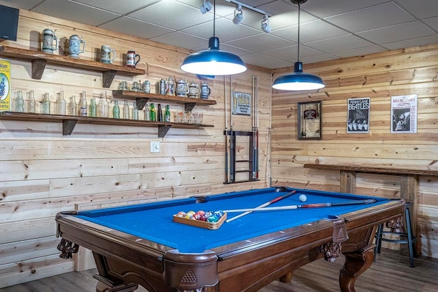 recreation room featuring dark wood finished floors, pool table, wooden walls, track lighting, and a drop ceiling