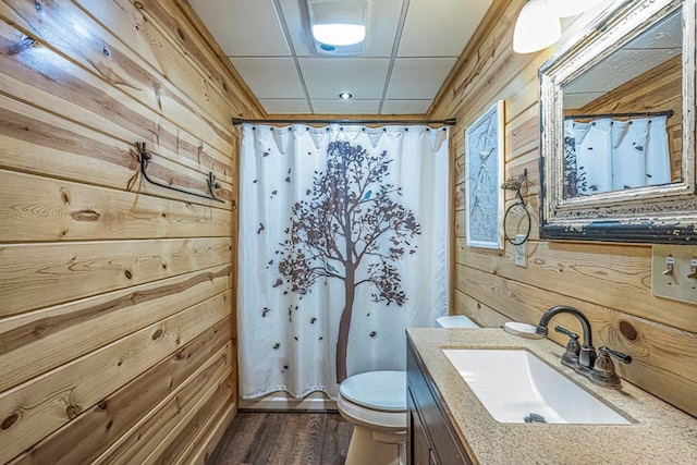 full bathroom with wood walls, a shower with shower curtain, vanity, and toilet