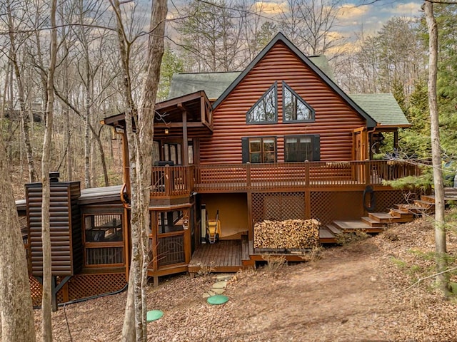 back of property featuring a shingled roof, a chimney, log veneer siding, and a deck