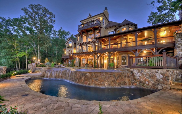 pool at night with pool water feature and a patio area