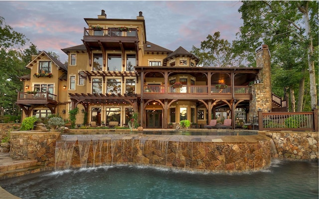 back house at dusk featuring a balcony