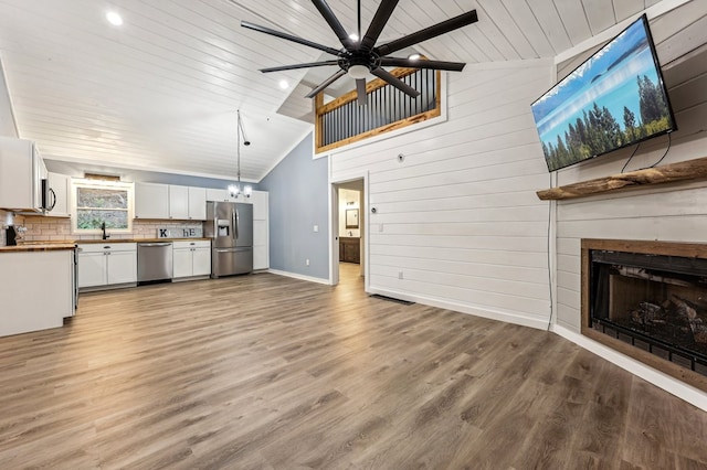 unfurnished living room with ceiling fan, light hardwood / wood-style flooring, sink, and high vaulted ceiling