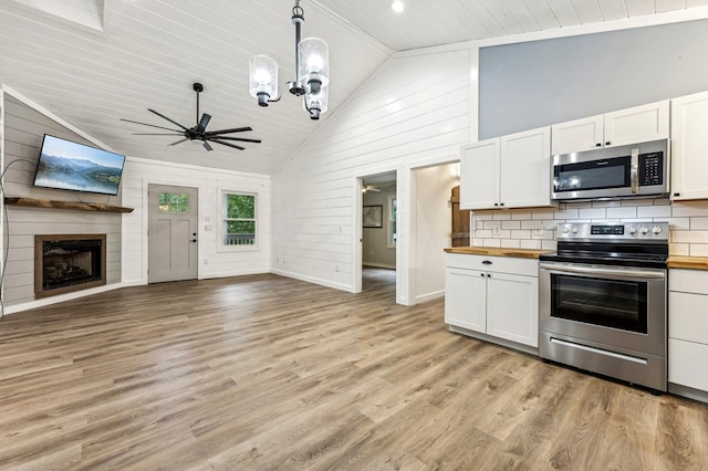 kitchen featuring high vaulted ceiling, white cabinets, appliances with stainless steel finishes, and wood counters