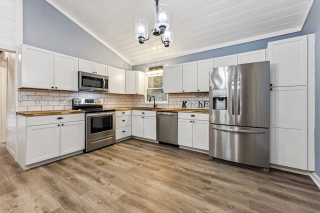 kitchen featuring light wood-type flooring, white cabinets, butcher block counters, hanging light fixtures, and stainless steel appliances