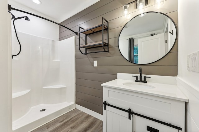 bathroom featuring wood walls, hardwood / wood-style flooring, a shower, and vanity