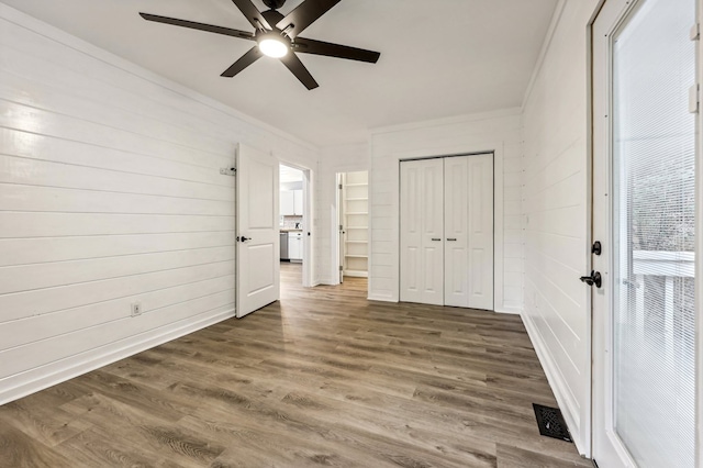 unfurnished bedroom featuring ornamental molding, a closet, ceiling fan, and dark wood-type flooring