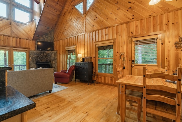 dining space with light hardwood / wood-style flooring, high vaulted ceiling, a fireplace, and a healthy amount of sunlight