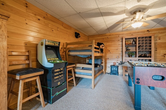 bedroom featuring a paneled ceiling, wooden walls, and carpet floors