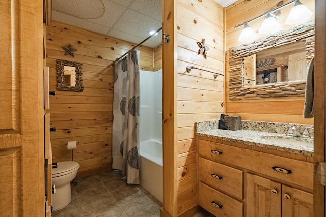 full bathroom with vanity, toilet, and wood walls