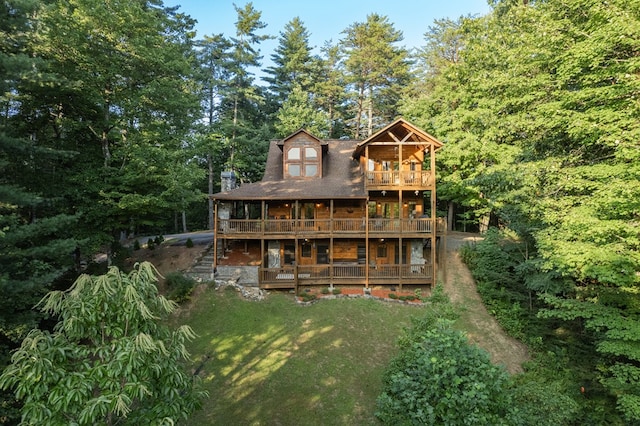 back of house featuring a balcony and a yard