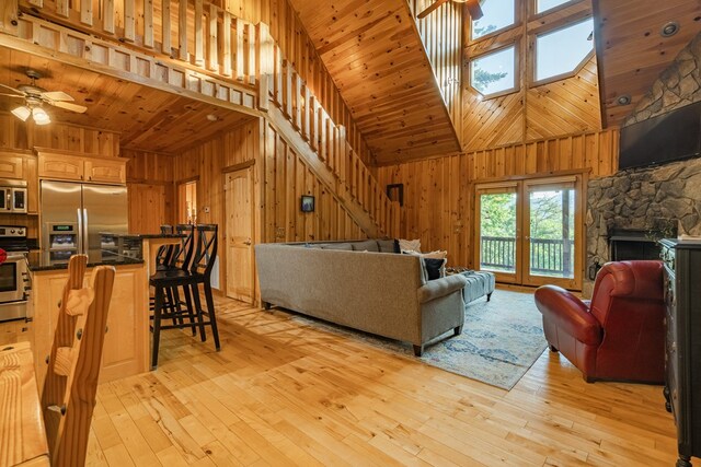 living room featuring ceiling fan, wood walls, and high vaulted ceiling