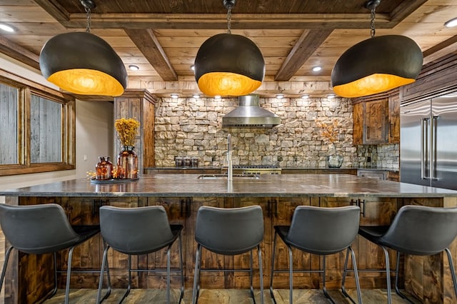 kitchen with wall chimney range hood, wood ceiling, beamed ceiling, and built in fridge