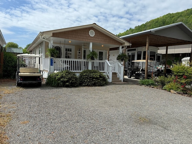 view of front facade featuring a detached carport, covered porch, and gravel driveway