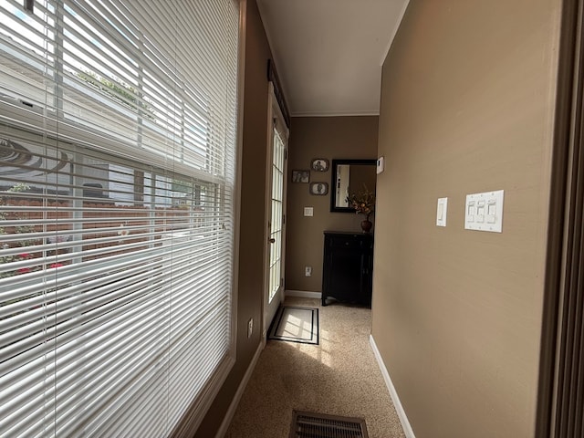 corridor featuring crown molding, baseboards, visible vents, and carpet