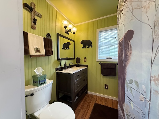 bathroom with vanity, toilet, baseboards, wood finished floors, and ornamental molding