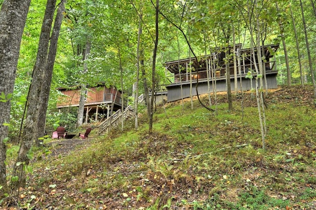 view of yard featuring a deck, stairway, and a wooded view