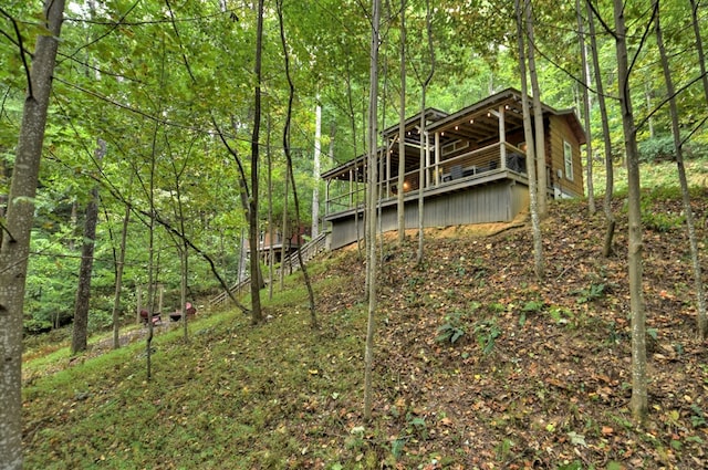 back of property with stairway, a wooded view, and a deck