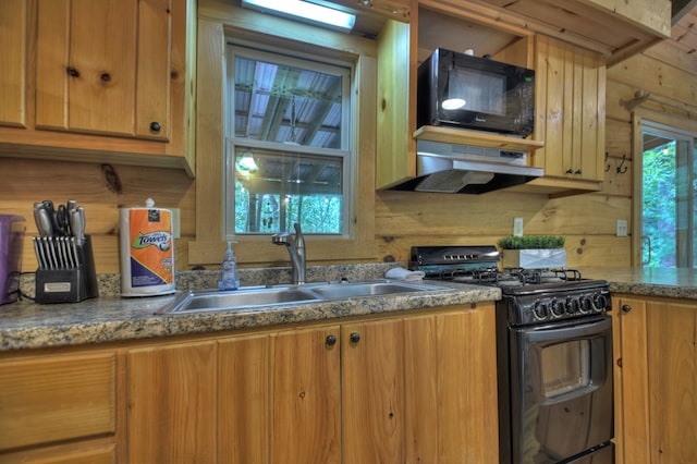 kitchen with under cabinet range hood, black appliances, brown cabinetry, and a sink
