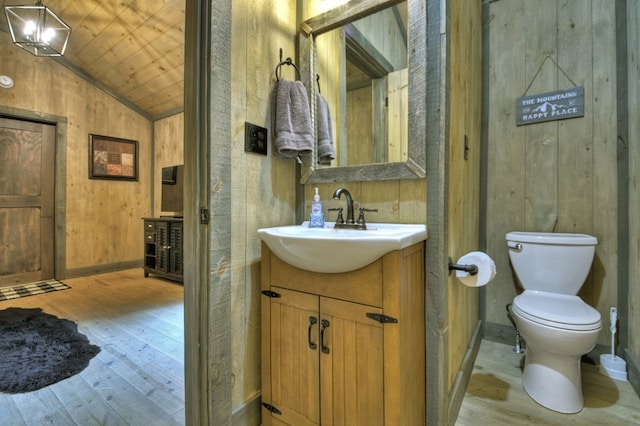 half bathroom featuring wood walls, hardwood / wood-style flooring, toilet, and vaulted ceiling